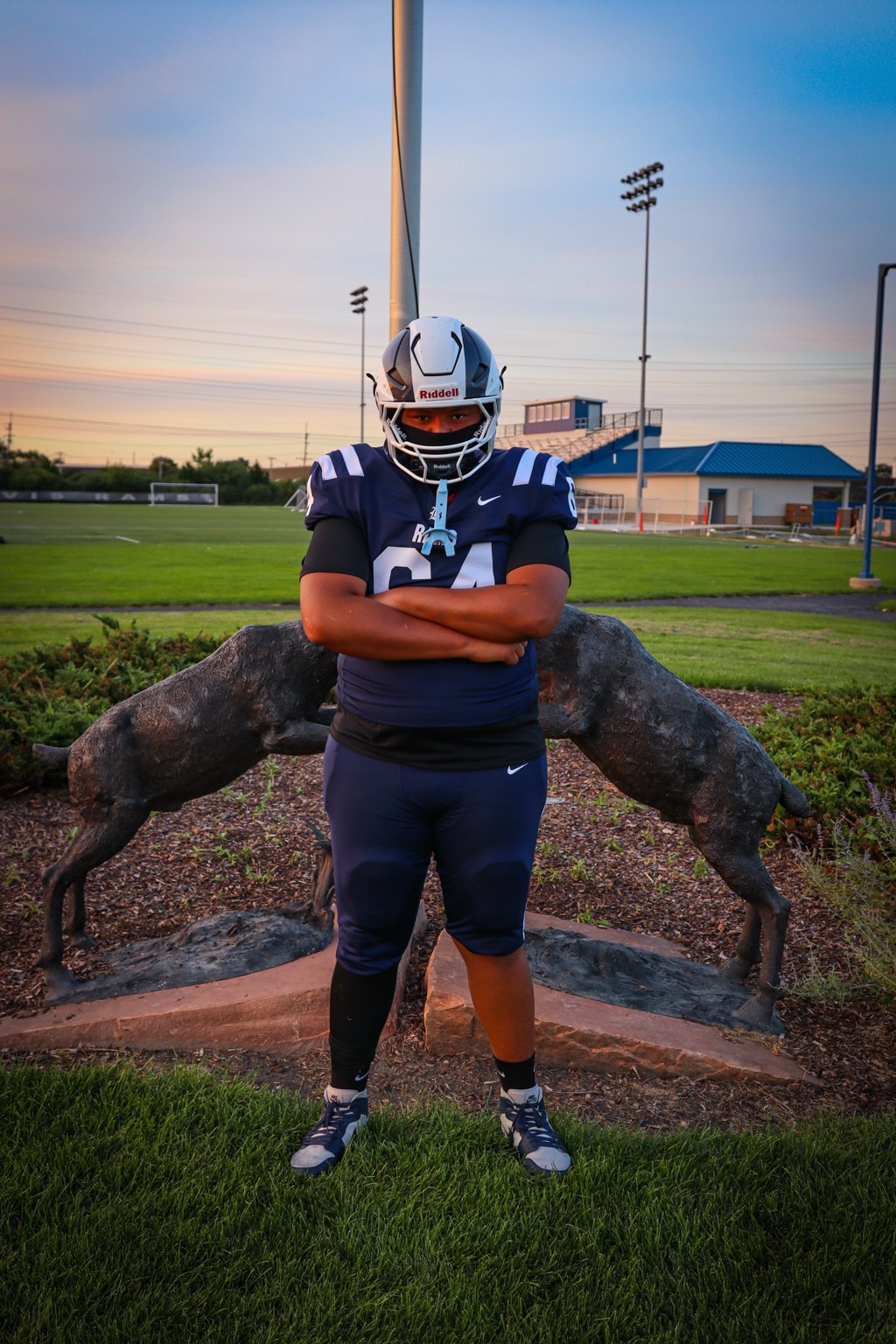 Football player posing in front of a ram statue
