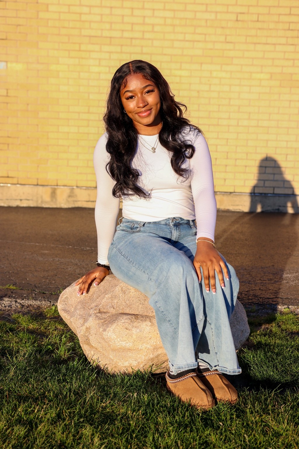 Golden hour seated portrait against a brick wall